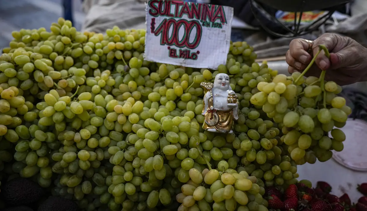 Sebuah patung Buddha diletakkan di atas buah anggur untuk dijual oleh pedagang kaki lima di pusat kota Santiago, Chile, Rabu (5/4/2022). Chile akan melonggarkan aturan protokol kesehatan Covid-19 pada 14 April dan berhenti mewajibkan penggunaan masker di ruang terbuka. (AP Photo/Esteban Felix)
