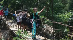 Sejumlah pelajar menyeberangi Kali Angke melewati jembatan rapuh di Kampung Cantiga, Petir, Cipondoh, Tangerang, Rabu (2/9/2015). Jembatan berusia lima tahun tersebut menghubungkan Cipondoh dan Kembangan, Jakarta. (Liputan6.com/Gempur M Surya)