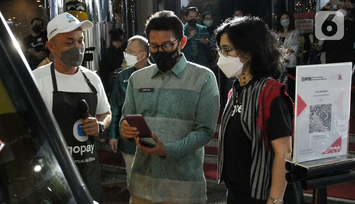 Menteri Pariwisata dan Ekonomi Kreatif Sandiaga Uno (tengah), VP Public Policy and Government Relations Gojek Tricia Iskandar dan Owner Yellow Bowl Foodtruck Adji Hardiansyah Iskandar mencoba pembayaran cashless QRIS GoPay di Food Truck Goes to Mandalika, Jakarta (13/03/2022).(Liputan6.com/HO/Ading)