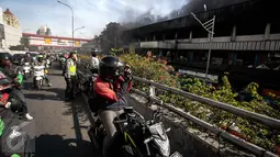 Seorang pengendara motor mengambil gambar kebakaran yang melanda Blok III Pasar Senen, Jakarta Pusat, Kamis (19/1). Banyak warga yang melintas melambatkan laju kendaraannya untuk melihat kebakaran Pasar Senen. (Liputan6.com/Faizal Fanani)