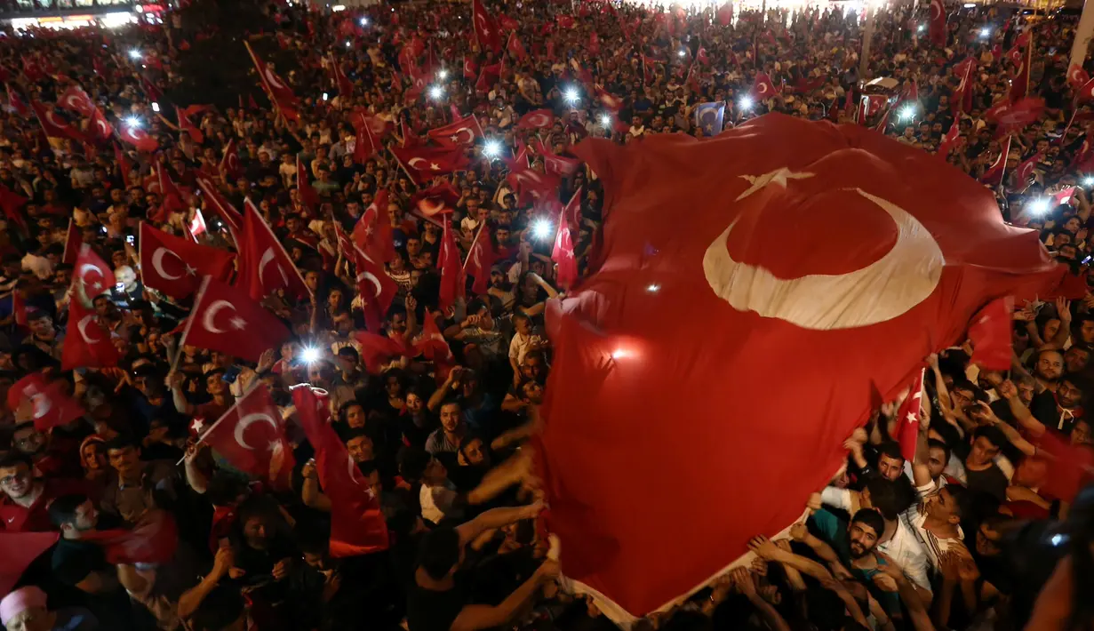 Pendukung Presiden Turki, Tayyip Erdogan mengibarkan bendera nasional mereka ketika berkumpul di Taksim Square, pusat kota Istanbul, Sabtu (16/7). Ratusan warga turun ke jalan untuk merayakan kegagalan kudeta militer di Turki. (REUTERS/Huseyin Aldemir)