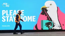 Seorang pria melewati tanda yang mendorong orang untuk tinggal di rumah saat pemberlakukan lockdown di Melbourne, Jumat (28/5/2021). Melbourne kembali menerapkan lockdown untuk keempat kalinya setelah wabah COVID-19 menyebar cepat di wilayah tersebut. (William WEST / AFP)