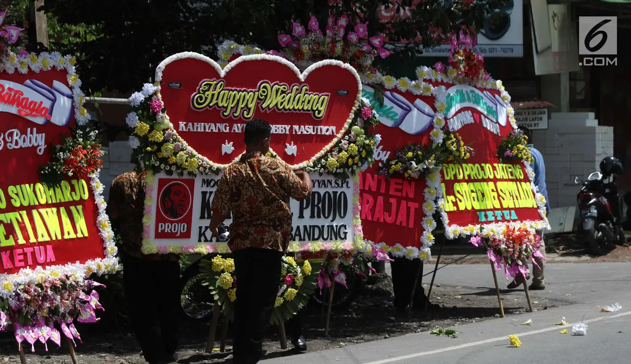 Warga melintas di depan karangan bunga untuk pernikahan Kahiyang-Bobby di sepanjang jalan menuju Gedung Graha Saba di Solo, Senin (6/11). Pernikahan putri Presiden Joko Widodo tersebut akan berlangsung pada Rabu (8/11) esok. (Liputan6.com/Angga Yuniar)