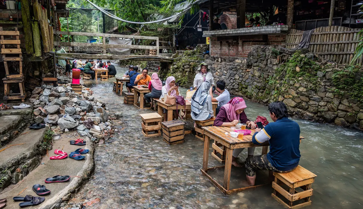 Pelanggan makan siang di restoran dengan meja di aliran sungai di Kampung Kemensah di pinggiran Kuala Lumpur pada 14 Juli 2020.(Mohd RASFAN / AFP)