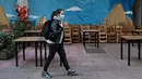 Seorang perempuan berjalan melewati restoran yang tutup di pusat kota Athena, Yunani, Selasa (16/11/2021). Pemilik restoran, kafe, dan bar melakukan pemogokan selama 24 jam, memprotes aturan terkait Covid-19 dan biaya energi yang tinggi. (Louisa GOULIAMAKI / AFP)
