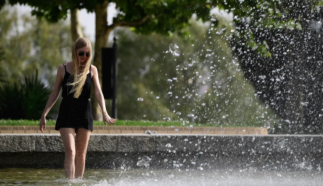 Seorang gadis mendinginkan kakinya di air mancur sebuah taman di dekat Kuil Debod di Madrid saat terjadi gelombang panas, Spanyol pada 13 Juli 2017. (AFP Photo/Javier Soriano)