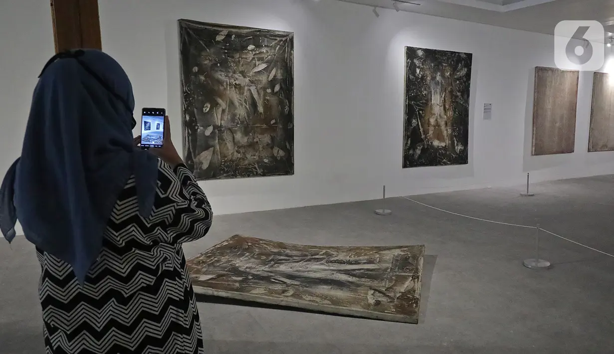 Pengunjung mengambil gambar karya yang dipajang dalam pameran Pulih di Pasar Seni, Ancol, Jakarta, Sabtu (14/11/20). Sebanyak 10 seniman Indonesia digandeng untuk pameran yang dibuka pada 14 sampai 29 November 2020 mendatang tersebut. (Liputan6.com/Herman Zakharia)
