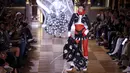 Bella Hadid mempersembahkan kreasi Thom Browne saat peragaan busana Musim Semi-Musim Panas 2023 sebagai bagian dari Paris Womenswear Fashion Week, Paris, Prancis, 3 Oktober 2022. Bella menambahkan sepasang sarung tangan merah dan meninggikan tinggi badannya dengan sepasang sepatu hak tinggi bertali hitam dengan kaus kaki wol berbintik-bintik. (Photo by Vianney Le Caer/Invision/AP)