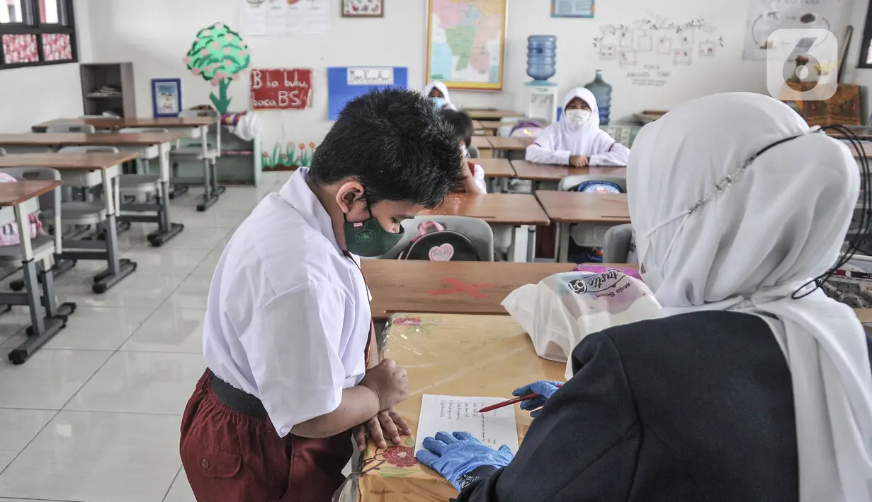 Guru mendampingi murid kelas 1 saat mengikuti Pembelajaran Tatap Muka (PTM) Terbatas di SDN Malaka Jaya 07 Pagi, Klender, Jakarta, Senin (30/8/2021). Kegiatan PTM terbatas ini akan berlangsung tiap Senin, Rabu, dan Jumat dengan jatah seminggu sekali per kelas. (merdeka.com/Iqbal S. Nugroho)