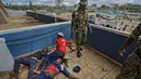 Seorang polisi berdiri di samping pendukung Presiden Kenya Uhuru Kenyatta yang terbaring tak sadarkan diri setelah dipukuli saat mereka mencoba menerobos gerbang, Nairobi, Kenya (28/11). (AP Photo / Ben Curtis)