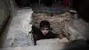 Seorang bocah berada di lubang menuju ruang bawah tanah Abu Omar di Douma, Damaskus, Suriah, (30/10). Abu Omar dibantu tetangganya berhasil menggali dan membangun ruangan di kedalaman 4 meter dari permukaan tanah. (AFP PHOTO/Sameer Al-Doumy)