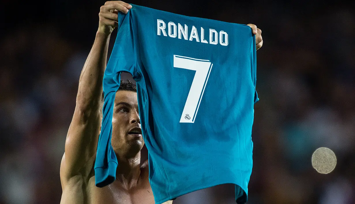 Pemain Real Madrid, Cristiano Ronaldo mengangkat jerseynya tinggi-tinggi di hadapan suporter Camp Nou pada leg pertama Piala Super Spanyol, Senin (14/8). Aksi selebrasi Ronaldo usai mencetak gol ke gawang Barcelona itu menjadi sorotan. (STRINGER/AFP)