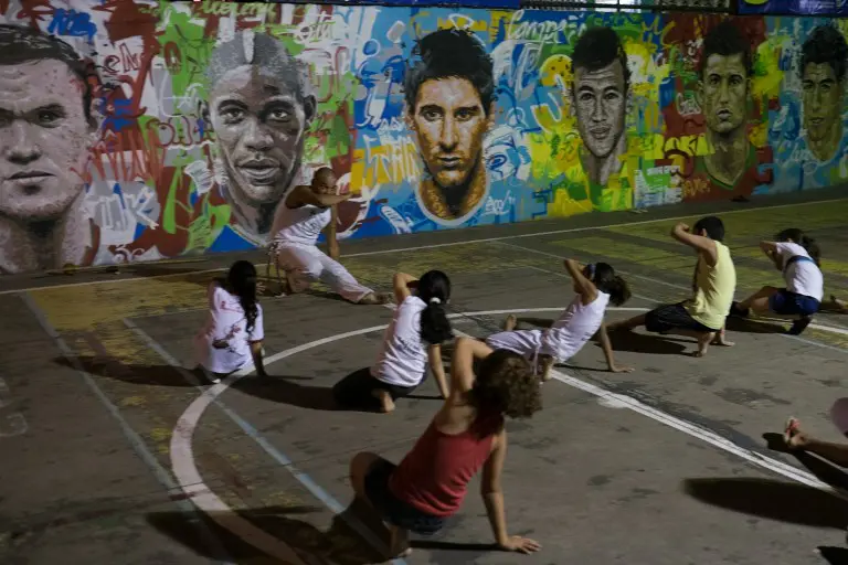 Anak-anak sedang berlatih seni bela diri khas Brasil Capoeira di dekat tembok lukisan wajah pemain top dunia, Brasil, Rabu (21/05/2014) (AFP PHOTO/Yasuyoshi CHIBA).