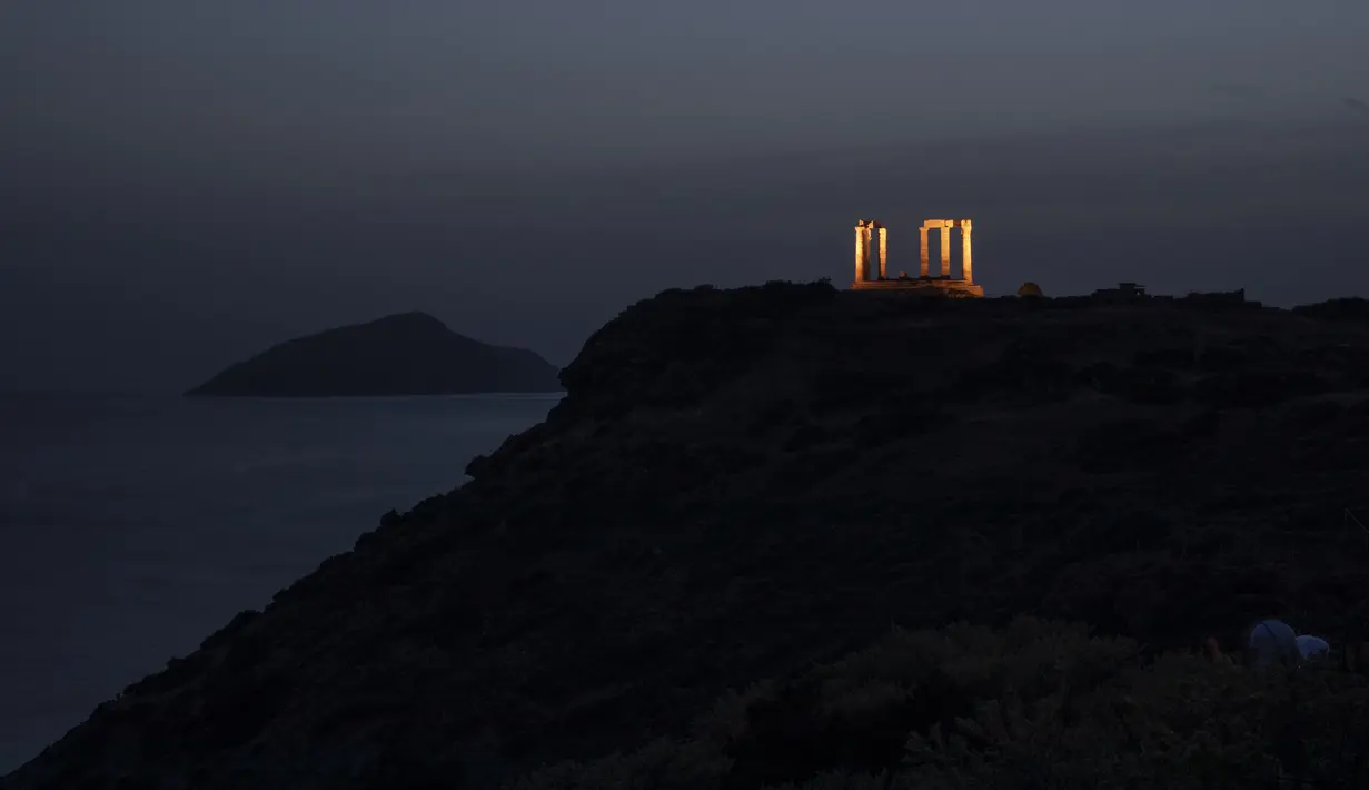 Pemandangan Kuil Poseidon yang bermandi cahaya di Cape Sounion, Athena, Yunani, Senin (18/5/2020). Yunani kembali membuka kota kuno Acropolis serta situs-situs lainnya setelah dua bulan ditutup selama lockdown akibat pandemi virus corona COVID-19. (AP Photo/Petros Giannakouris)