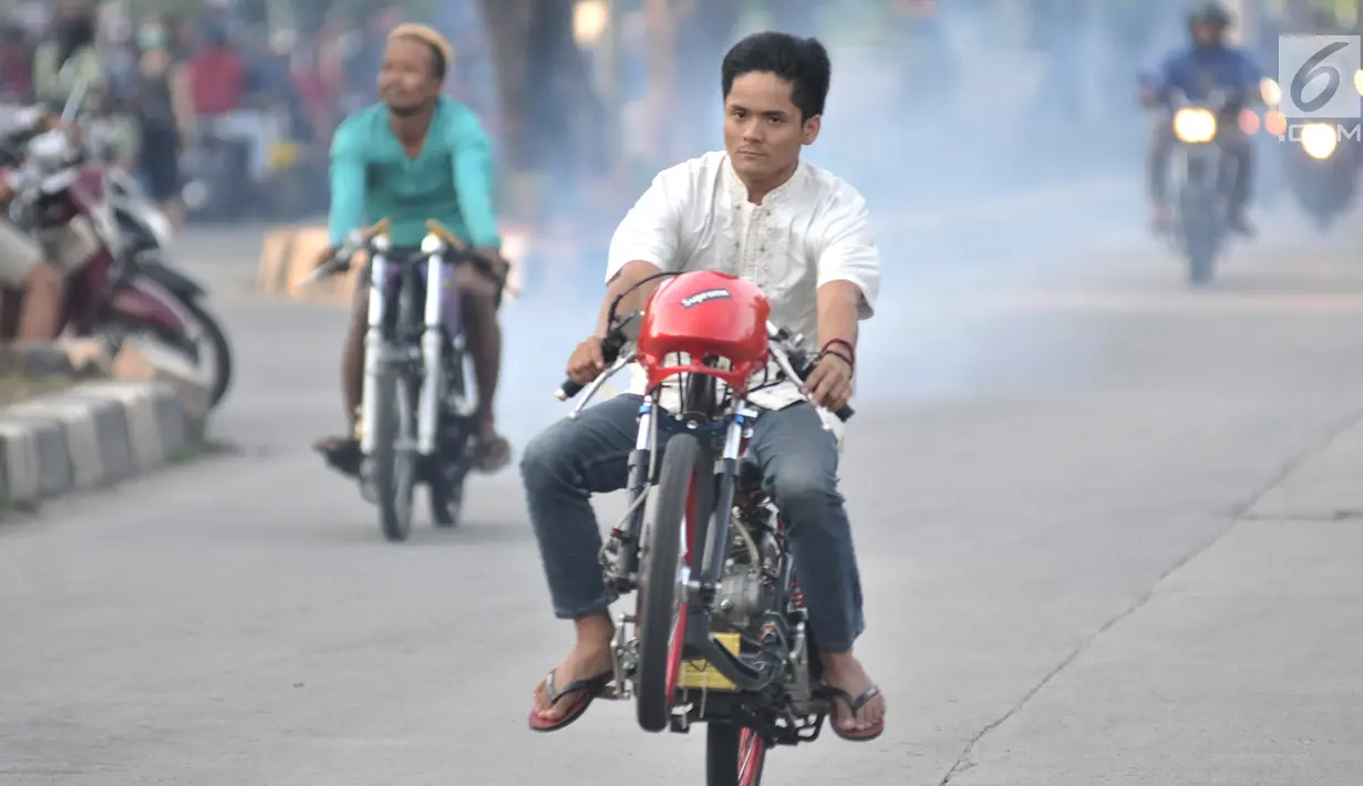 Seorang pembalap mengangkat sepeda motornya saat ikut dalam balapan liar di Jakarta, Minggu (27/5) pagi. Mereka memanfaatkan sepinya arus lalu lintas kendaraan untuk balapan liar. (Merdeka.com/Iqbal S Nugroho)