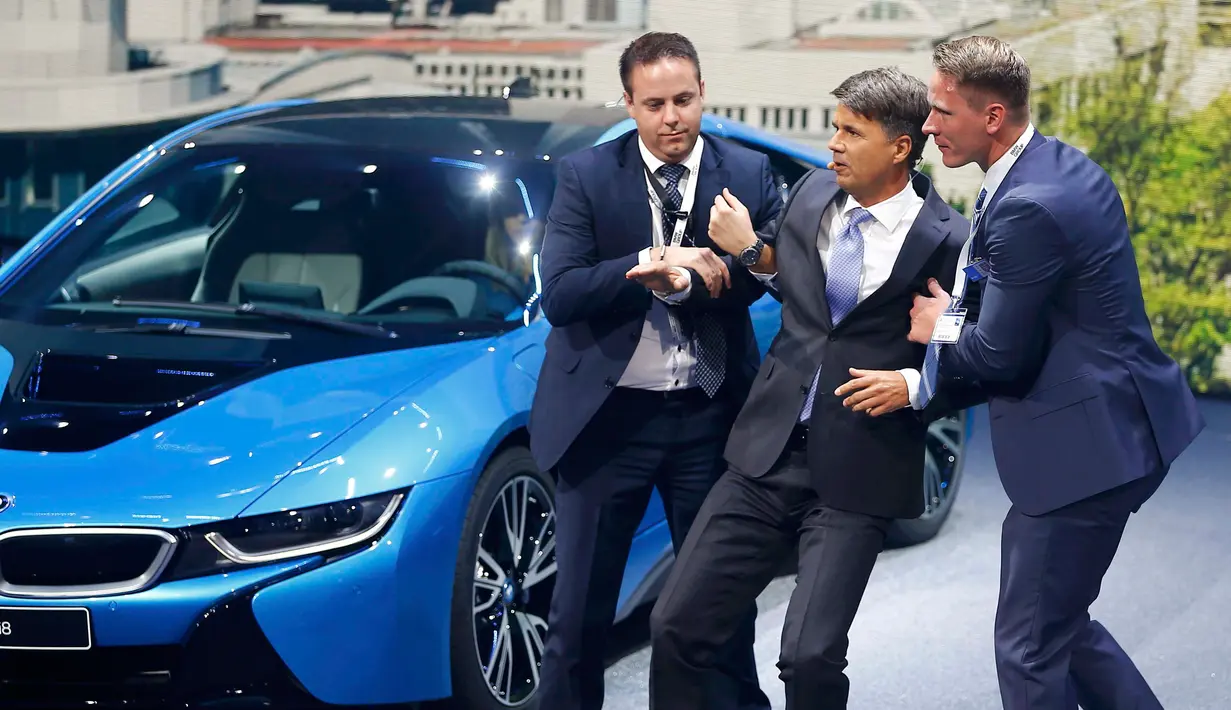 Dua orang tampak membantu CEO BMW, Harald Krueger yang jatuh pingsan saat sedang presentasi selama Frankfurt Motor Show (IAA) di Jerman, Selasa (15/9). Krueger jatuh ketika tengah memberikan ulasan mengenai produk terbaru BMW. (REUTERS/Kai Pfaffenbach)
