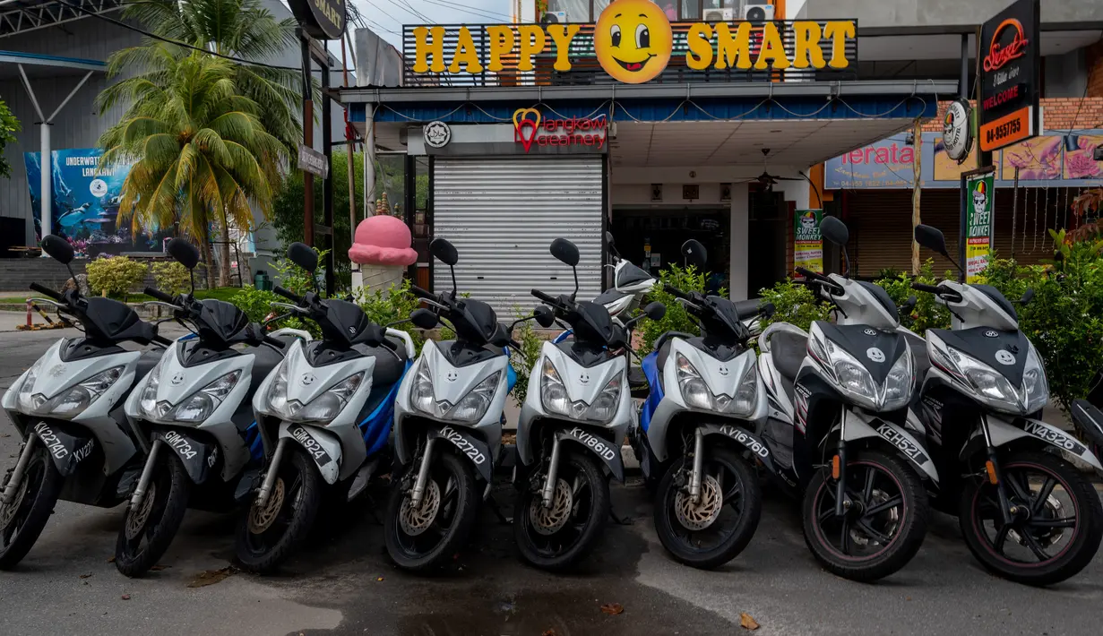 Sepeda motor sewaan terlihat diparkir di jalan di tujuan wisata Pantai Cenang di pulau  Langkawi, yang ditutup untuk sebagian besar pengunjung luar karena penguncian sebagian yang ditetapkan pihak berwenang untuk mengekang penyebaran Covid-19, di Kedah, Malaysia utara (18/11/2020). (AFP/Mohd Rasfan)