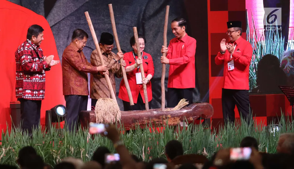 Presiden Jokowi , Wapres Jusuf Kalla, Presiden ke-3 BJ Habibie dan Ketum PDIP Megawati Soekarnoputri menumbuk padi saat acara Rakornas Tiga Pilar PDI P di ICE BSD, Tangerang Selatan, Sabtu (16/12). (Liputan6.com/Angga Yuniar)