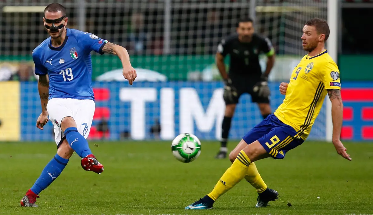 Pemain  Italia, Leonardo Bonucci menendang bola melewati pemain Swedia, Marcus Berg pada laga leg kedua playoff Piala Dunia 2018 di Stadion San Siro, Selasa (14/11). Swedia lolos ke Rusia 2018 berkat keunggulan agregat 1-0. (AP/Antonio Calanni)