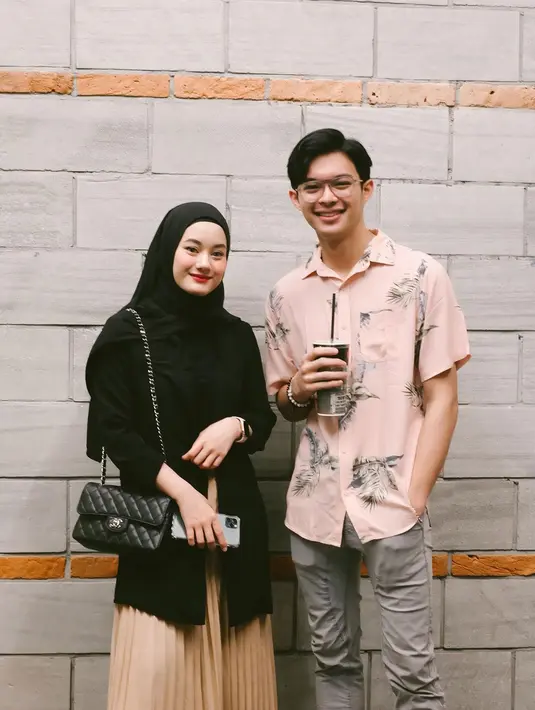 Outfit feminin Dinda Hauw bisa jadi inspirasi first date untuk pengguna hijab. Ia padukan pleated skirt, kemeja, dan hijab hitam [@dinda_hw]