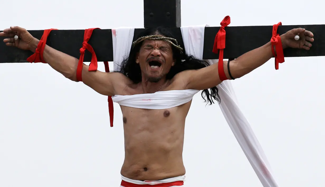 Ruben Enaje merintih ketika tangannya dipaku ke tiang salib di Pampanga, Filipina, Jumat (30/3). Aksi tersebut dilakukan dalam rangka visualisasi penderitaan Yesus Kristus menyambut Jumat Agung. (AP Photo/Aaron Favila)