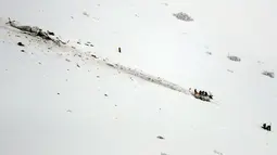 Petugas mendekati helikopter yang jatuh di kawasan ski Campo Felice, Italia, Selasa (24/1). Berdasarkan laporan awal helikopter tersebut jatuh usai menjemput seseorang yang terluka akibat kecelakaan ski. (AP Photo)