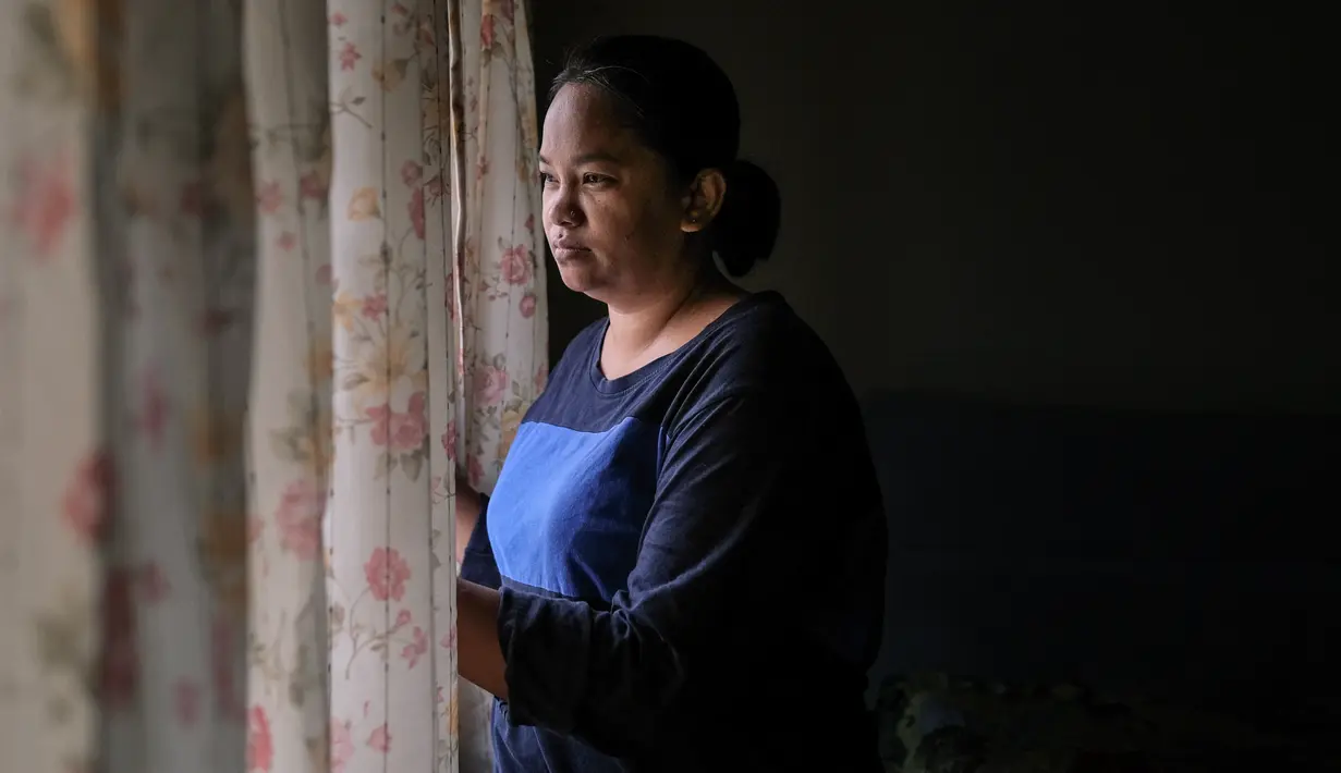Ibu tunggal Tilda Kalaivani melihat keluar jendela dari apartemen sewaannya di Kuala Lumpur pada 6 Juli 2021. Warga Malaysia yang berjuang untuk memenuhi kebutuhan sehari-hari selama pandemi virus corona yang memburuk, telah mengibarkan bendera putih untuk memohon bantuan. (Mohd RASFAN/AFP)