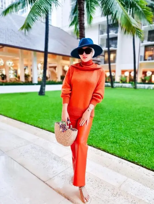 Berlibur ke Hawaii, Syahrini tampil nyentrik dalam balutan busana serba oranye. Penampilannya pun diperlengkap dengan topi fedora berwarna biru, kacamata hitam, dan tas jinjing di lengannya. (Instagram/princesssyahrini).