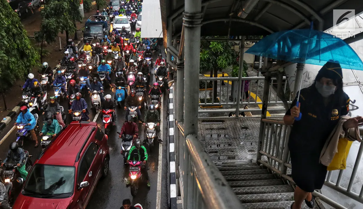 Pejalan kaki melewati jembatan penyeberangan orang (JPO) saat kendaraan terjebak kemacetan di Jalan Jenderal Ahmad Yani, Jakarta, Selasa (2/4). Hujan deras yang mengguyur Jakarta menyebabkan sejumlah jalan tergenang banjir hingga mengakibatkan kemacetan. (Liputan6.com/JohanTallo)
