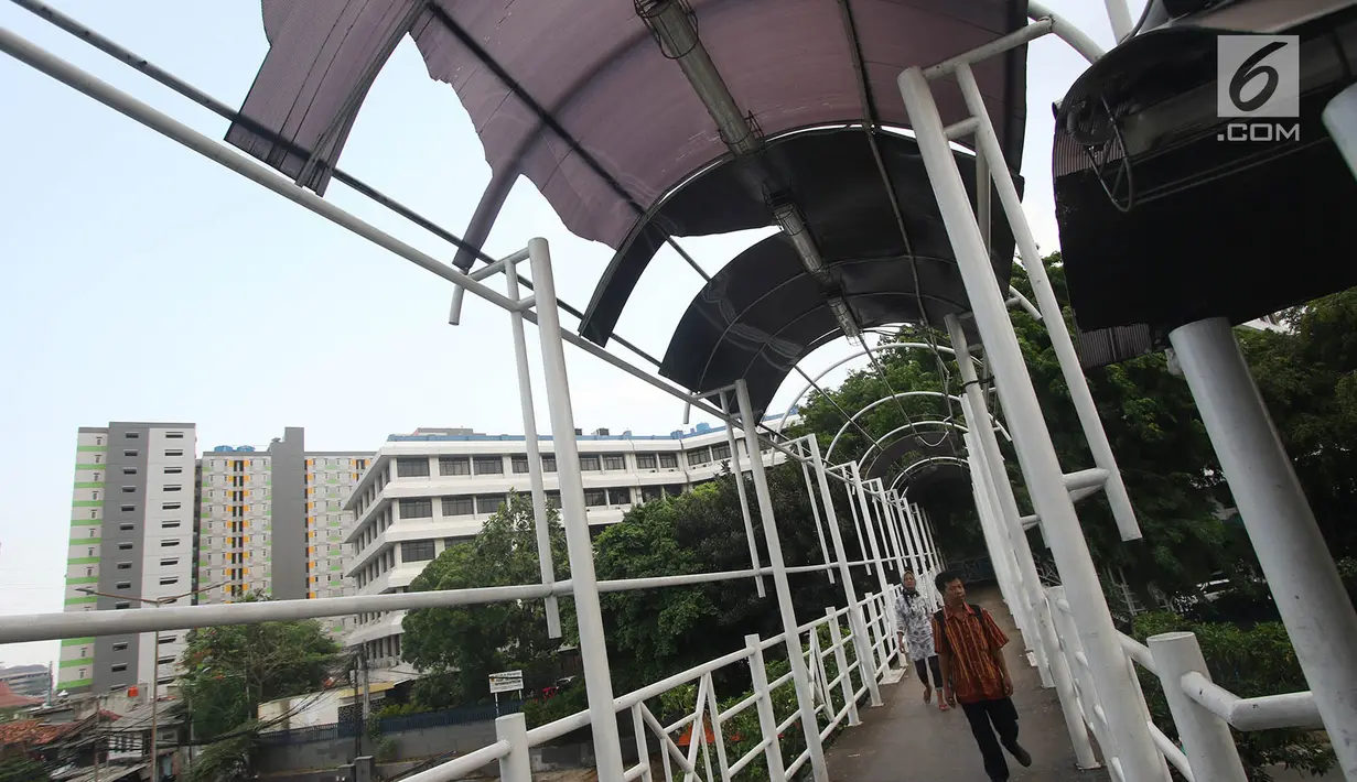 Pejalan kaki melintasi Jembatan Penyeberangan Orang (JPO) tanpa atap dan berkarat di Petamburan, Tanah Abang, Jakarta, Selasa (24/10). Selain itu kondisi tersebut juga membahayakan keselamatan pejalan kaki. (Liputan6.com/Immanuel Antonius)