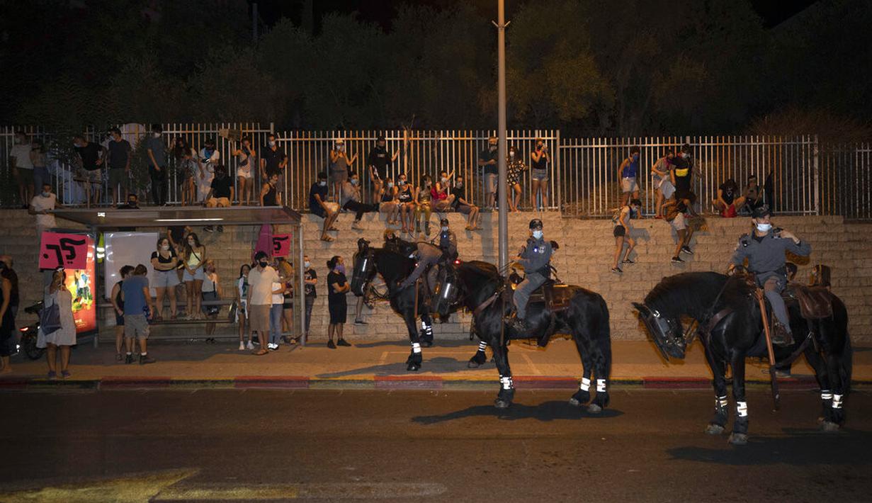 Polisi yang menunggang kuda berdiri di depan pengunjuk rasa selama demonstrasi menentang tindakan lockdown di Tel Aviv, Israel, Kamis (1/10/2020). Pengunjuk rasa meyakini lockdown ditujukan untuk mengekang protes terhadap Perdana Menteri Israel Benjamin Netanyahu. (AP Photo/Sebastian Scheiner)