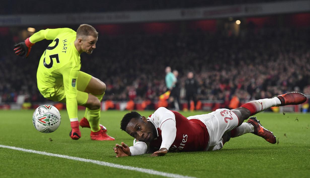 Pemain Arsenal, Danny Welbeck (kanan) jatuh saat berebut bola dengan kiper West Ham United, Joe Hart pada laga Piala Liga Inggris di Emirates Stadium, London, (19/12/2017). Arsenal menang 1-0. (AFP/Ben Sransall)