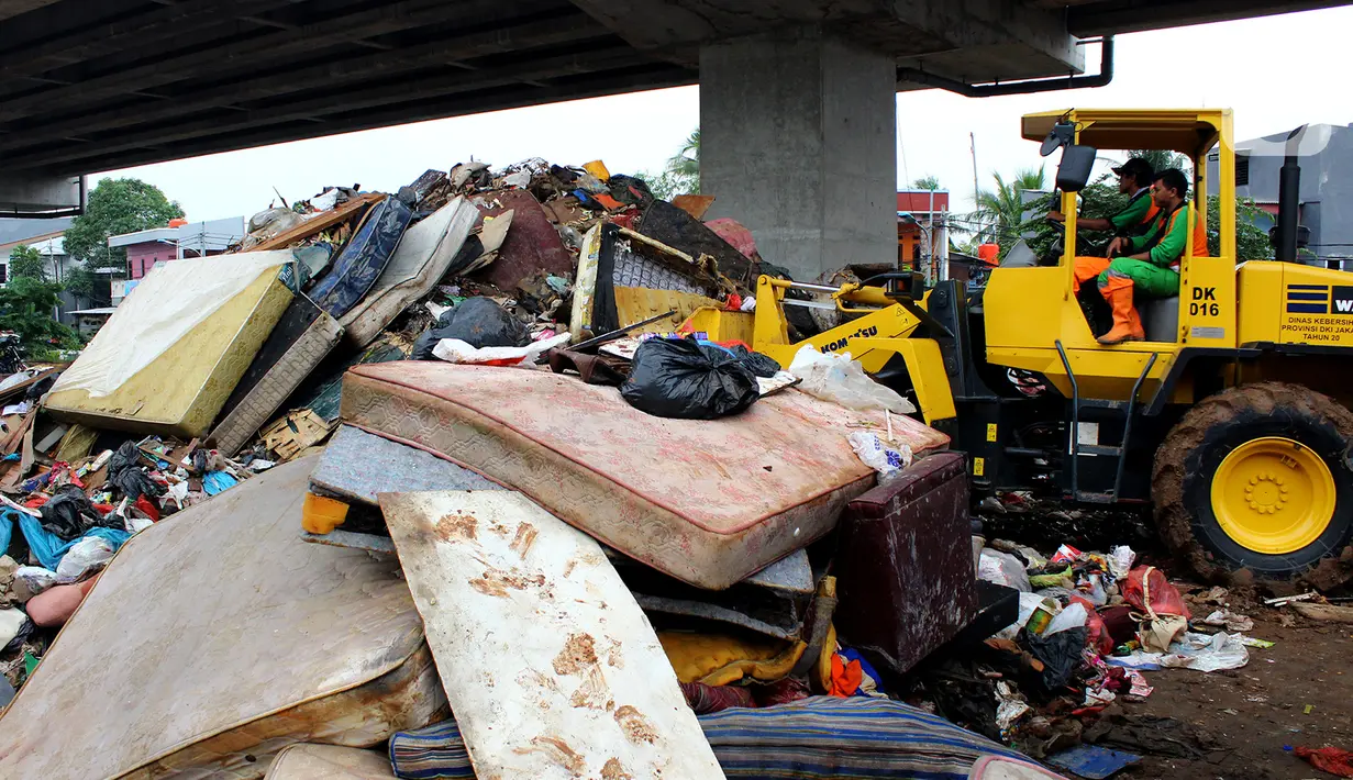 Petugas PPSU DKI Jakarta menggunakan alat berat saat membersihkan sampah sisa banjir di bawah Tol Becakayu, Cipinang Melayu, Jakarta Timur, Rabu (8/1/2020). Sampah sisa banjir tersebut selanjutnya diangkut ke TPA Bantar Gebang. (merdeka.com/Magang/Muhammad Fayyadh)
