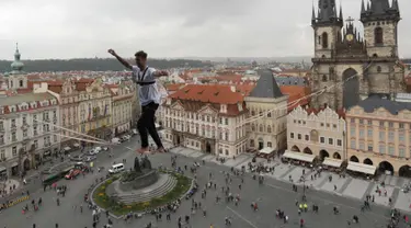 Atlet menyeimbangkan tubuhnya saat berjalan di atas tali yang membentang di Old Town Square, Praha, Republik Ceko, (25/9). Pertunjukan tersebut merupakan bagian kampanye dukungan bagi orang-orang yang hidup dengan diabetes. (AP Photo/Petr David Josek)