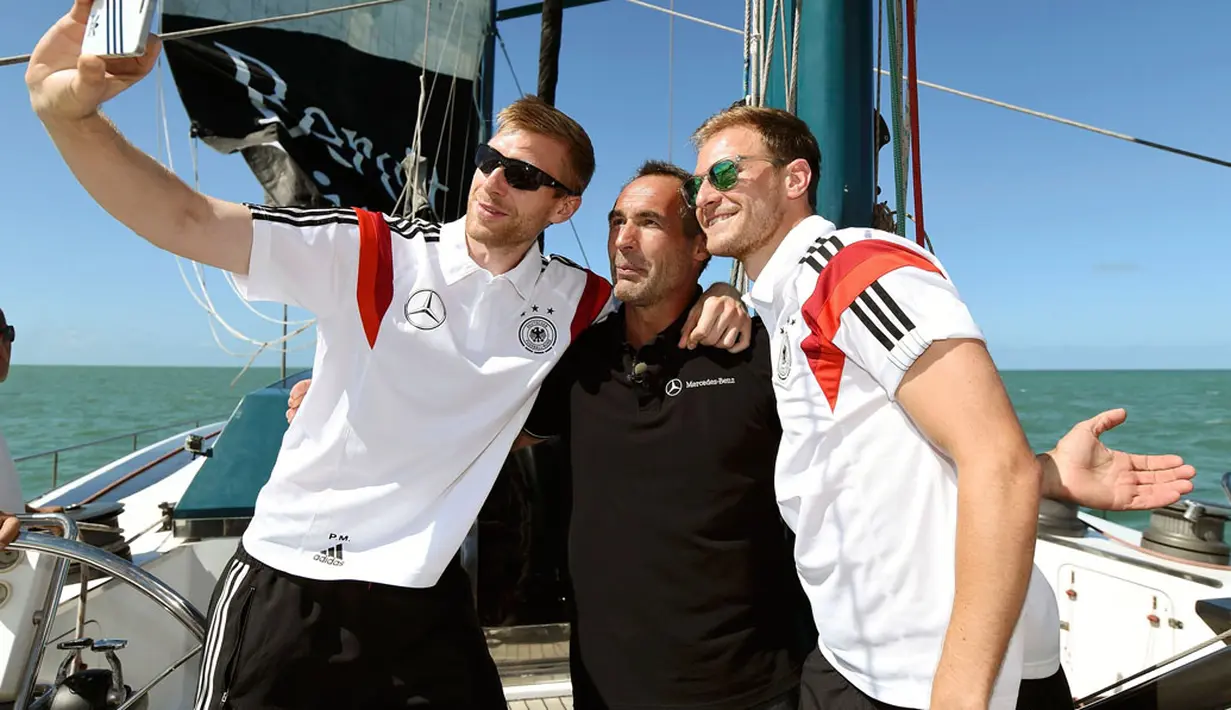 Pemain Timnas Jerman, Per Mertesacker (kiri) dan Benedikt Hoewedes berfoto bersama dengan petualang Mike Horn (tengah) di atas kapal saat berlayar di salah satu pantai dekat Santo Andre, Sao Paolo, Brasil, (10/6/2014). (AFP PHOTO/Markus Gilliar) 