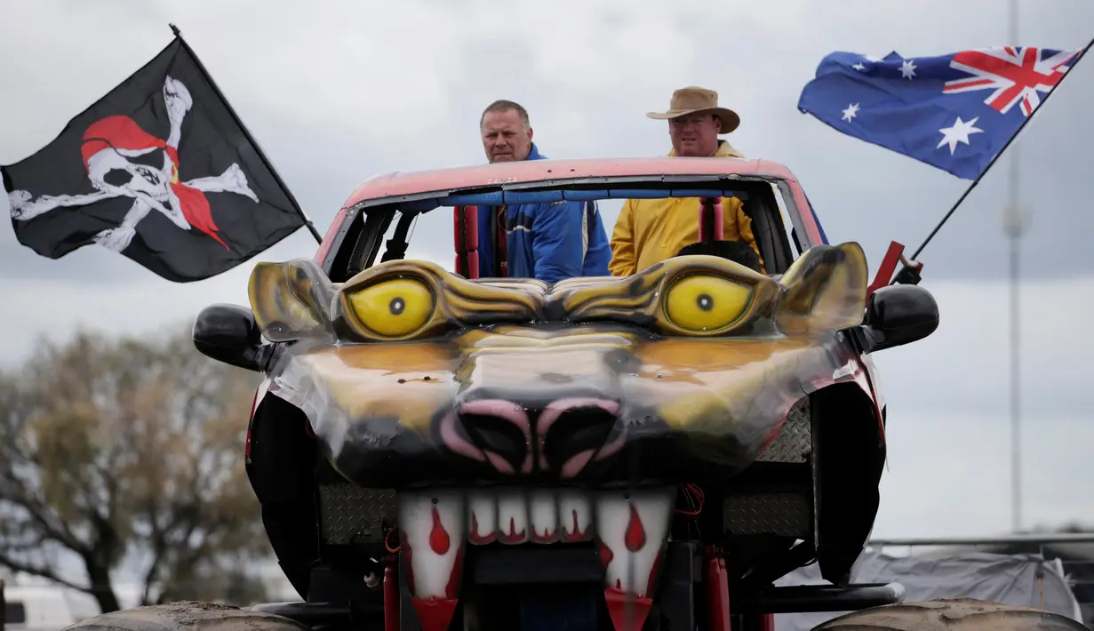 Seorang pengemudi mengendarakan truk raksasa yang dihiasi wajah monster berbendera Australia dan bajak laut saat menyaksikan sebuah pertandingan balap di ajang Festival Deni Ute Muster di Deniliquin, New South Wales, (30/9). (REUTERS/Jason Reed)