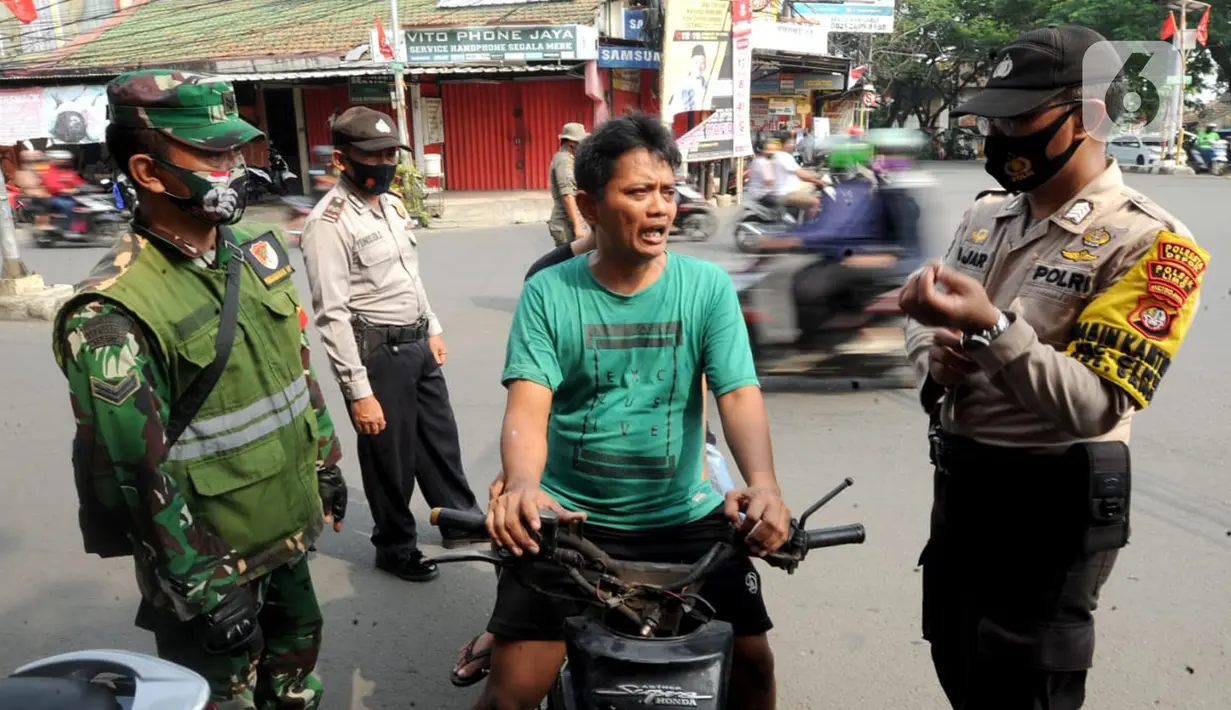 Anggota TNI-Polri menghentikan warga yang tidak mengenakan masker saat razia gabungan Kelurahan Gandul di Perempatan Gandul, Cinere, Depok, Kamis ( 29/08/2020). (merdeka.com/Arie Basuki)