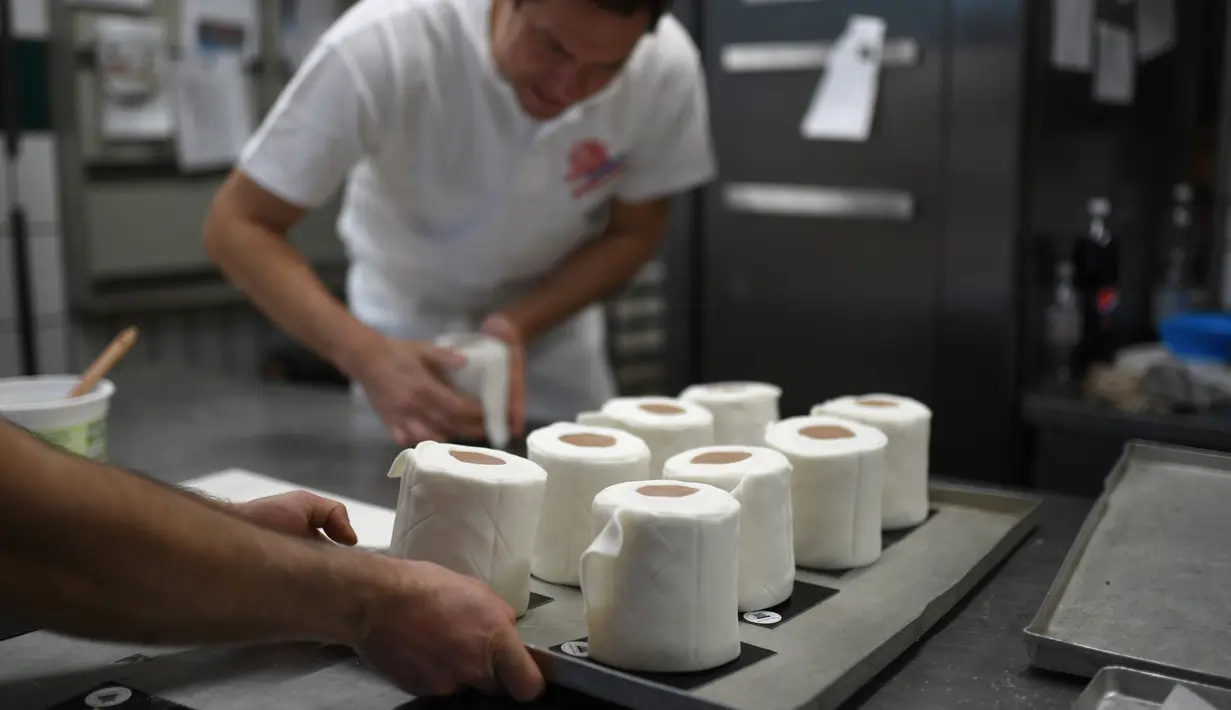 Pemilik toko roti Tim Kortuem menyiapkan kue berbentuk tisu toilet di toko roti Schuerener Backparadies di Dortmund, Jerman, 26 Maret 2020. Kelangkaan kertas tisu toilet memunculkan ide bagi pemilik toko roti itu membuat kue menyerupai barang yang diburu warga di tengah Covid-19 (Ina FASSBENDER/AFP)