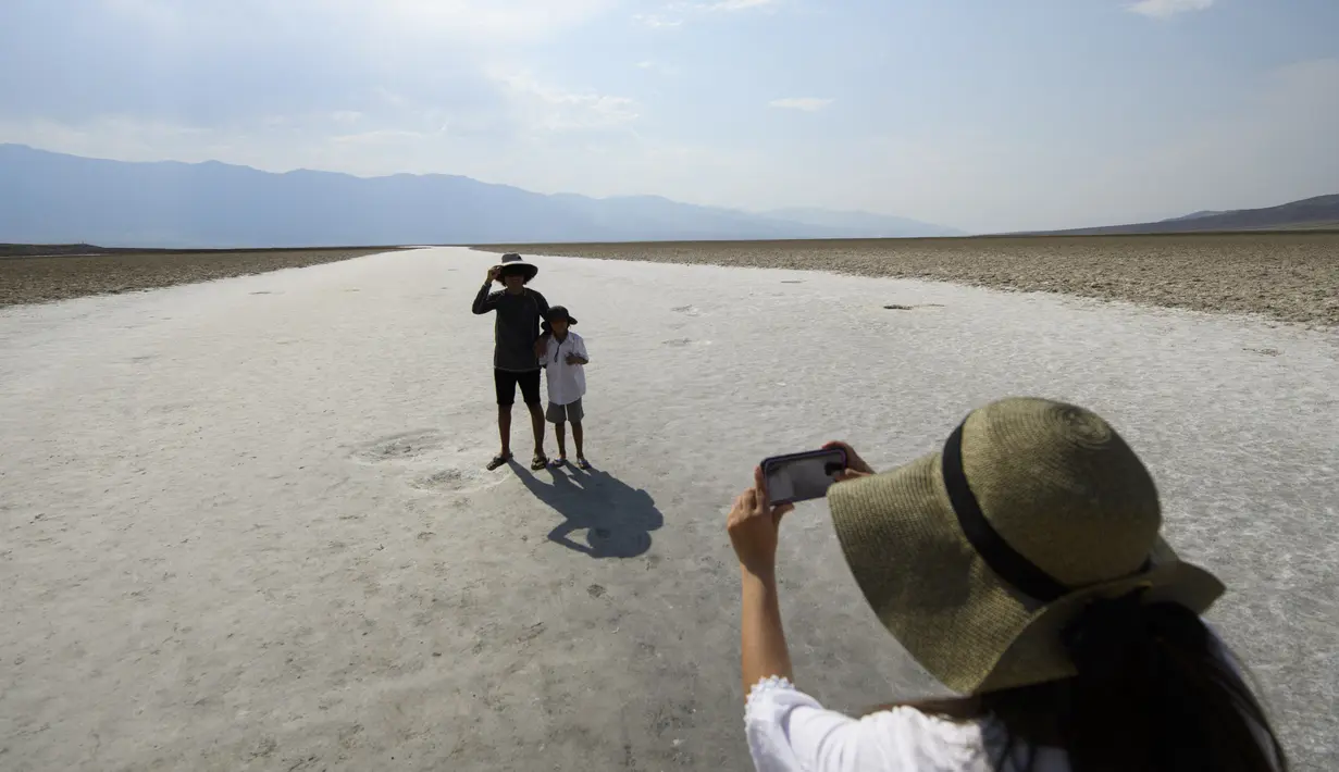 Pengunjung berfoto di dataran garam Badwater Basin, Taman Nasional Death Valley, California, Kamis (17/6/2021). National Park Service memperingatkan cuaca musim panas yang ekstrem, mendesak wisatawan untuk membawa air ekstra dan "perjalanan yang disiapkan untuk bertahan hidup". (Patrick T. FALLON/AF