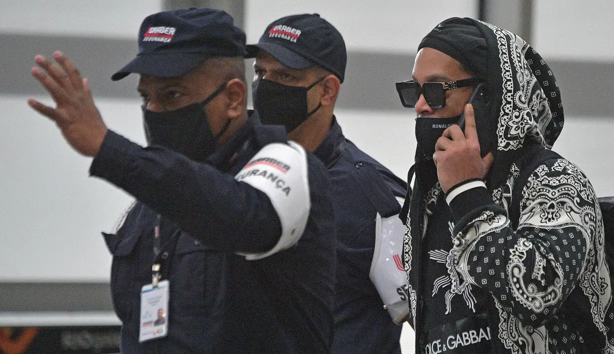 Mantan pemain timnas Brasil, Ronaldinho (kanan) tiba di bandara El Galeao di Rio de Janeiro, setelah menjalani tahanan rumah di Paraguay, Selasa (25/8/2020). Ronaldinho menghirup udara bebas setelah lima bulan menjadi tahanan rumah karena memasuki Paraguay dengan paspor palsu. (Carl DE SOUZA/AFP)