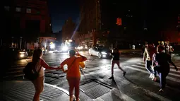 Pejalan kaki menyeberang jalan yang gelap saat terjadi pemadaman listrik di New York, AS, Sabtu (13/7/2019). Tidak ada keterangan mengenai pemadaman listrik yang terjadi di New York. (AP Photo/Michael Owens)