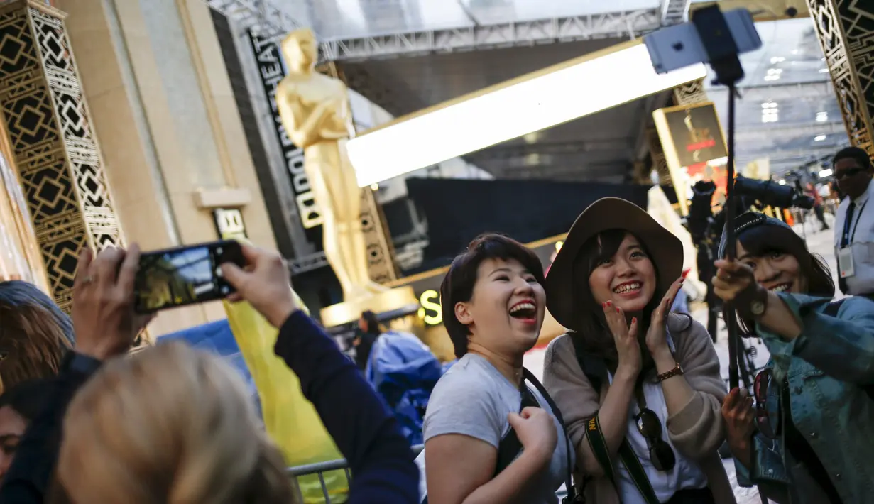 Wisatawan dari Jepang berselfie dengan latar belakang patung Oscar 2016 di luar Teater Dolby, Hollywood, California, Sabtu (27/2). Acara penghargaan Academy Awards ke-88 ini akan berlangsung pada Minggu (28/2) waktu setempat. (REUTERS/Adrees Latif)