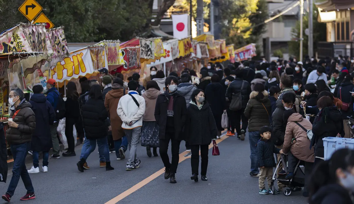 Orang-orang berkumpul di jalan "bebas kendaraan" yang dipenuhi oleh pedagang di luar kuil Yushima Tenmangu di Tokyo pada Hari Tahun Baru, Jumat (1/1/2021). (AP Photo/Hiro Komae)