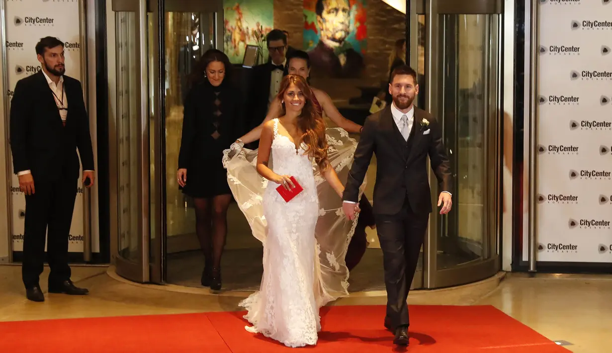 Bintang Barcelona, Lionel Messi, menggandeng sang istri, Antonella Roccuzzo, kelar dari ruang resepsi pernikahan untuk menemui wartawan Kompleks City Center, Santa Fe, Jumat (30/6/2017). (EPA/David Fernandez)