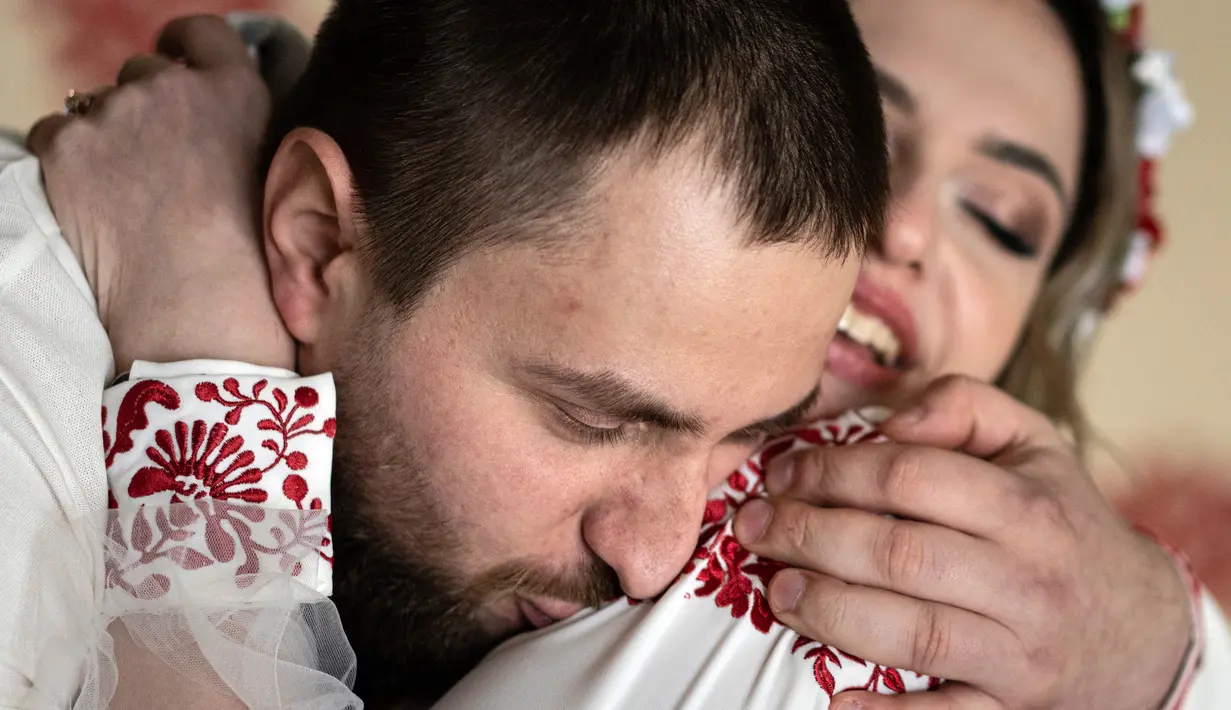 Tentara Ukraina Vitalii Khroniuk mencium istrinya Anna Sokurenko saat upacara pernikahan mereka di Kiev, Ukraina, 7 Februari 2023. Sadar bahwa dia bisa mati kapan saja, pria berusia 29 tahun itu memutuskan untuk mencoba cryopreservasi - proses pembekuan sperma atau sel telur yang dilakukan oleh beberapa tentara Ukraina karena mereka menghadapi kemungkinan tidak akan pernah pulang. (AP Photo/Evgeniy Maloletka)