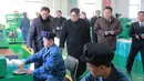 Gambar yang dirilis pada Kamis (25/1), menunjukkan pemimpin Korea Utara, Kim Jong-un didampingi istrinya, Ri Sol-Ju (belakang) melihat-lihat pegawai pabrik yang tengah bekerja saat mengunjungi pabrik farmasi di Pyongyang. (KCNA VIA KNS/AFP)