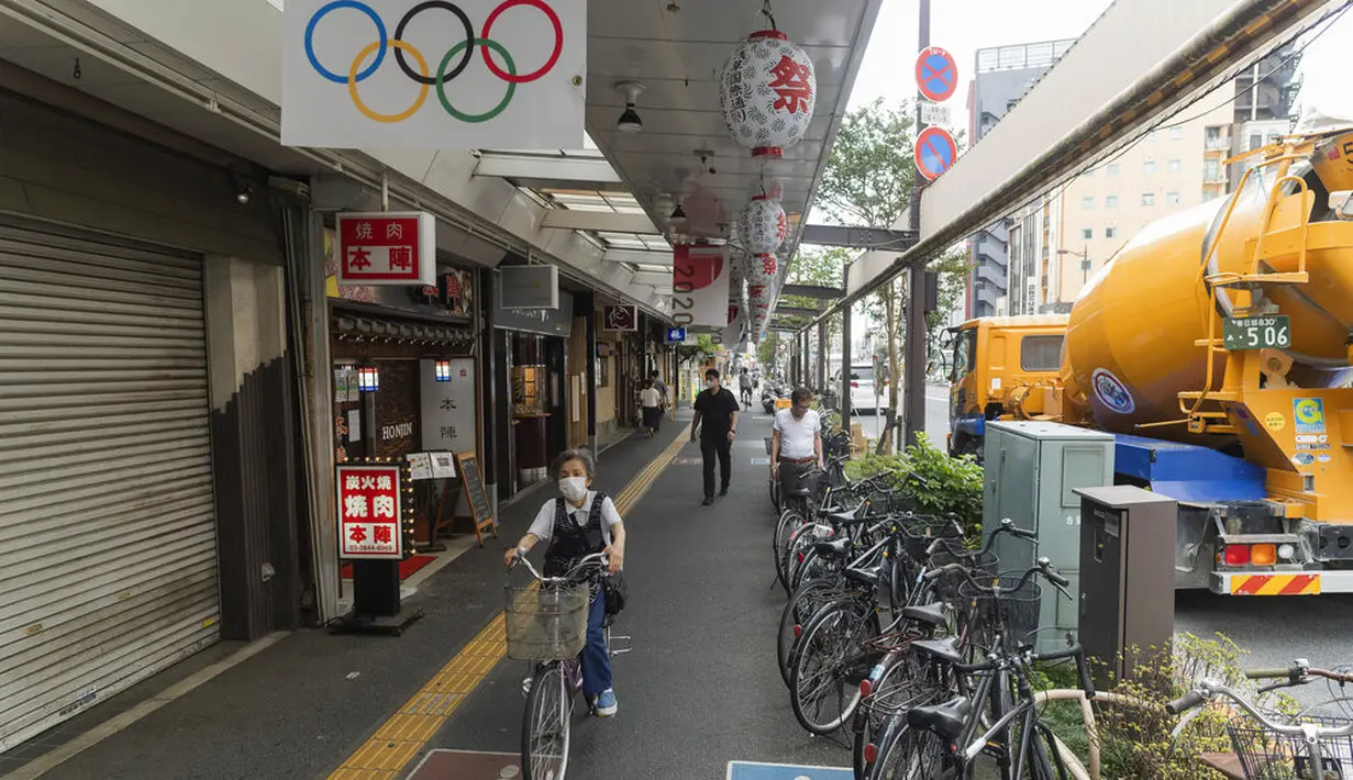Seorang perempuan mengendarai sepeda di trotoar dengan hiasan Olimpiade di Tokyo, Kamis (15/7/2021). Penyelenggaraan Olimpiade Tokyo akan didadakan di bawah keadaan darurat covid-19 yang diumumkan di Ibu Kota Jepang. (AP Photo/Hiro Komae)