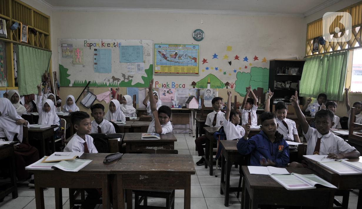 Siswa korban banjir mengangkat tangan saat ditanya oleh guru di SDN Bukit Duri 11, Jakarta, Senin (6/1/2020). Banjir menyebabkan sekitar 50 persen siswa SDN Bukit Duri 11 tidak masuk sekolah karena mayoritas tinggal di kawasan Kampung Melayu dan Kampung Pulo. (merdeka.com/Iqbal S. Nugroho)