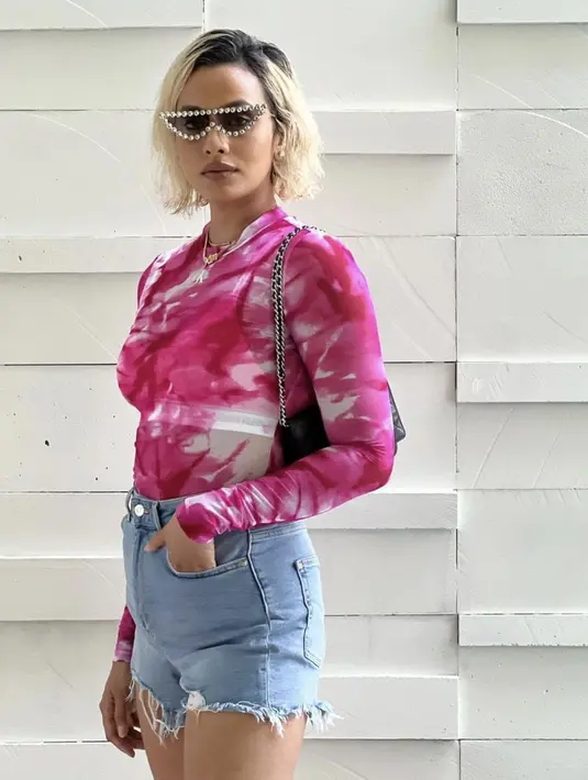 <p>Mengenakan kemeja tie dye bernuansa pink, celana pendek denim, dan kacamata hitam dengan aksen mutiara, sempurnakan gaya blink-blink yang seru seperti Barbie. [Foto: Instagram/ Kimmy Jayanti].</p>