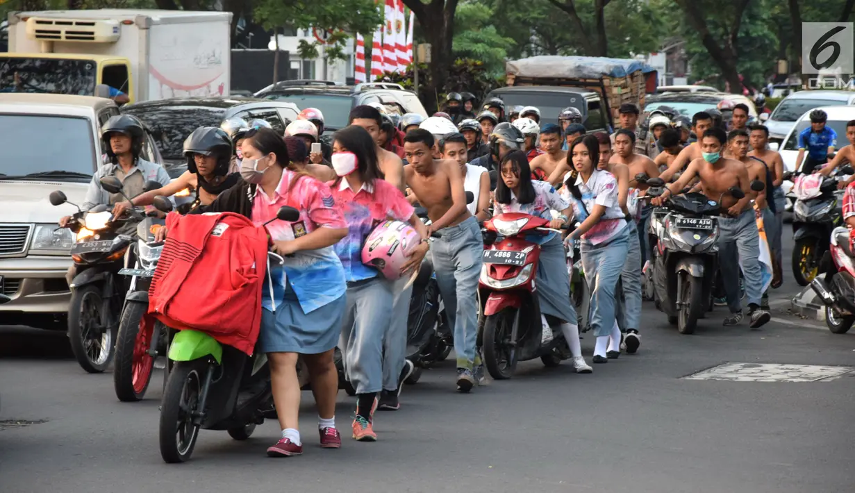 Ratusan pelajar SMA mendorong sepeda motor mereka di Bundaran Simpang Lima, Semarang, Jawa Tengah, Kamis (3/5). Aparat Polrestabes Semarang mengamankan mereka karena mengendarai motor tanpa helm. (Liputan6.com/Gholib)
